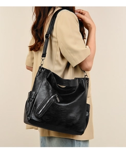 Detail view of large capacity black soft leather tote bag with side pockets and zippers