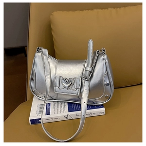 Detailed close-up of metallic silver underarm bag with heart buckle and metal studs