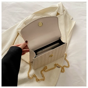 Detail of straw woven bag interior with magnetic closure and gold chain strap