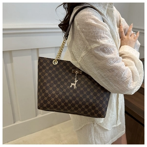 Detailansicht der Vintage-Tragetasche mit Kleeblattmuster und goldener Kette am Modell