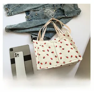 Détail d'un sac cabas en velours côtelé avec imprimé fraises et doubles poches devant