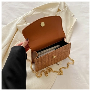 Macro view of interior storage capacity in woven straw bag with metal chain strap