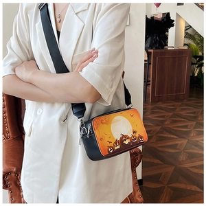 Detail of black synthetic leather crossbody bag featuring orange Halloween pumpkin print