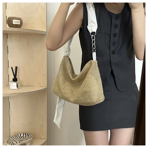 Detail of woven straw tote bag with white leather strap and silver chain accent