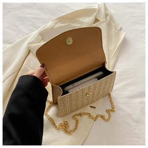 Detail of straw woven crossbody bag showing golden chain and smartphone storage capacity