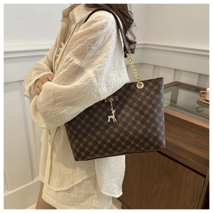 Detail einer braunen Shopper-Tasche mit goldenen Sternmustern und Hirsch-Anhänger