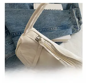 Detail of white pleated leather bag with smooth silver zipper and thin shoulder strap