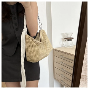 Detail of hand-woven straw tote with white fabric strap and metallic chain link