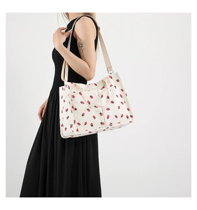 Détail du sac cabas en velours côtelé blanc à motifs fraises et bandoulière tissée