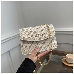 Detail of beige straw bag with V-shaped weave and golden butterfly clasp closure