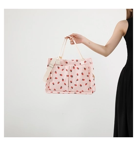 Vue détaillée du sac cabas en velours côtelé rose avec imprimé fraise et sangles blanches