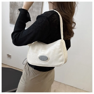 Detailed view of a white underarm bag with landscape texture and silver logo plate