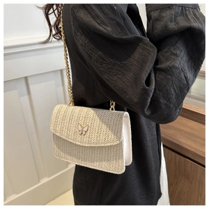 Detailed view of beige woven straw texture and elegant golden butterfly buckle on crossbody bag