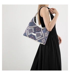 Detail of geometric woven tote bag with blue ethnic patterns and wide white shoulder strap