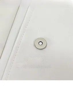 Detail der silbernen Magnetschnalle an weißer Stofftasche mit hochwertiger Naht