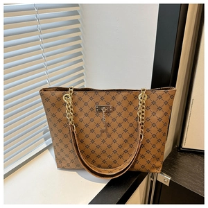 Detail der braunen Shopper-Tasche mit Kleeblatt-Print, Goldkette und Hirsch-Anhänger