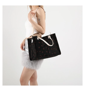 Détail de sac cabas en velours noir à motif fraise avec bandoulière blanche réglable
