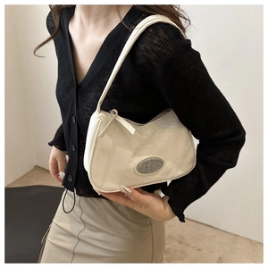 Close-up of beige moon-shaped hobo bag with sleek metal plate on smooth leather