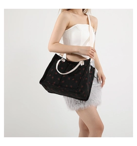 Détail du sac cabas en velours côtelé noir avec motif fraise et bretelles blanches