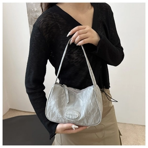 Detail shot of silver-grey hobo bag featuring marble-textured fabric and metal logo plaque