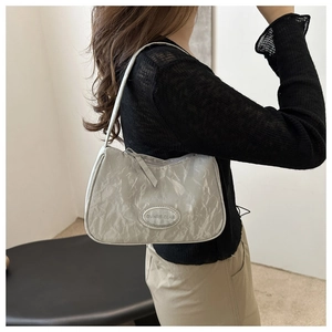 Detail of silver gray underarm bag with landscape texture finish and metal logo
