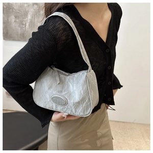 Detail of silver metallic hobo bag with unique pleated texture and oval brand logo tag
