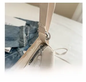 Close-up of smooth silver metal zipper and hardware on a beige pleated tote bag