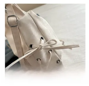 Detail view of cream tote bag featuring side drawstring bow and adjustable silver buckle