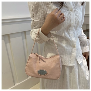 Detail of light pink shoulder bag with mountain ripple texture and silver metal logo plate