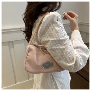 Detail of light pink shoulder bag with silver logo plaque and pleated texture finish