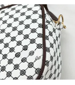 Detail of white leather bag featuring black clover pattern and premium stitching
