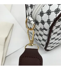 Detailed close-up of clover pattern on white leather with golden metal hardware hooks