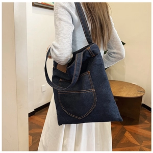 Detail of dark blue denim tote bag with contrast stitching and dual handle straps