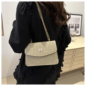 Detail of hand-woven straw bag with butterfly clasp and golden metal chain strap