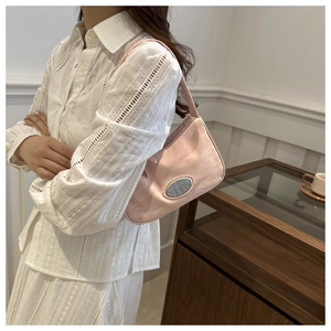 Detail of pink underarm bag with pleated leather texture and oval metal logo plate