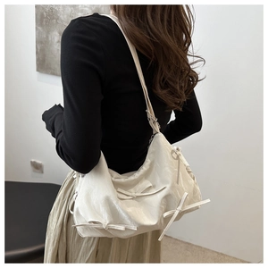 Detail view of cream crossbody bag with silky fabric and three decorative bows