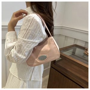 Detail showing pink leather underarm bag with silver logo plaque on white lace outfit