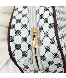 Macro detail of gold-plated metal zipper pull and clover pattern on white crossbody bag