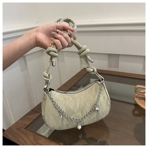 Detail of light green ruched handbag featuring pearl and star charms with knotted strap