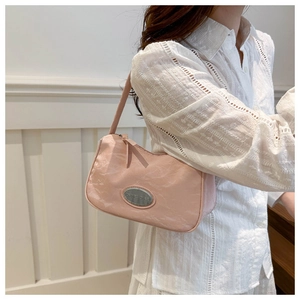 Close-up of pink hobo bag with pleated texture and silver brand plaque detail