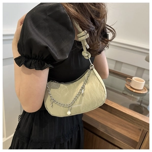 Detail of light green crescent bag with pleated texture, silver chain and pearl charm