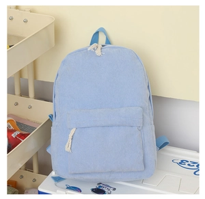 Détail d'un sac à dos en velours côtelé bleu clair avec texture côtelée et poche zip