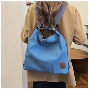 Detail view of denim canvas bag with adjustable strap and vintage leather brand label