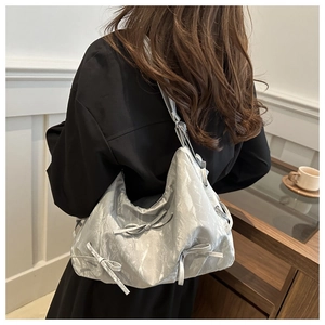Details einer silbernen Metallic-Schultertasche mit Plissee-Struktur und Schleifendekor