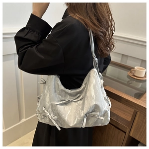 Details der silbernen Metallic-Schultertasche mit stilvollen Schleifendetails