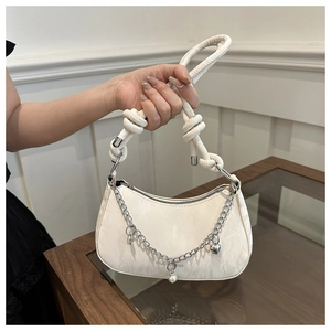 Close-up of white crescent bag with silver chain, pearl charms, and woven shoulder strap