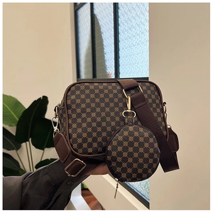 Close-up of brown monogram crossbody bag with wide strap and small round pouch attachment