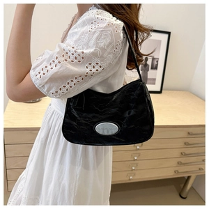 Detail of black wrinkled hobo bag featuring a silver oval metal plaque with engraving