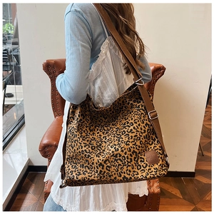 Macro view of leopard print canvas shoulder bag with adjustable brown strap and logo detail