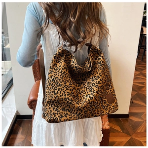Close-up of leopard print canvas tote bag with brown fabric shoulder strap on model